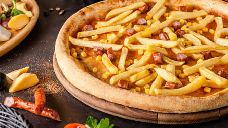 Italian Cuisine. Thin Oktoberfest pizza with french fries, hunting sausages and corn. Background image. copy spaceの写真素材
