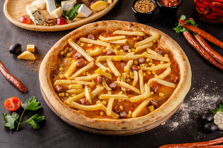 Italian Cuisine. Thin Oktoberfest pizza with french fries, hunting sausages and corn. Background image. copy spaceの写真素材