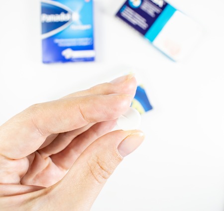 Medical background with multi-colored packs of pills. ?oncept pharmacy, clinic, drugs, headache medicine. Image on illness, flu, treatment. Hand holding a pillの写真素材