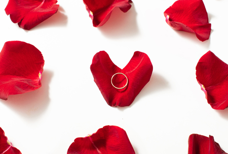 White gold engagement ring with diamonds in a heart shaped box and roses on white isolated backgroundの写真素材