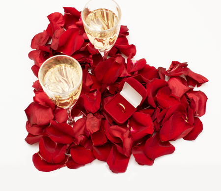 White gold engagement ring with diamonds in a heart shaped box and roses on white isolated backgroundの写真素材