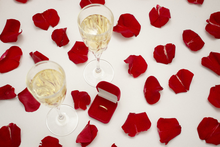 White gold engagement ring with diamonds in a heart shaped box and roses on white isolated backgroundの写真素材