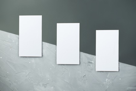 ockup of a three business cards placed vertically with shadows on a gray background. White card on...