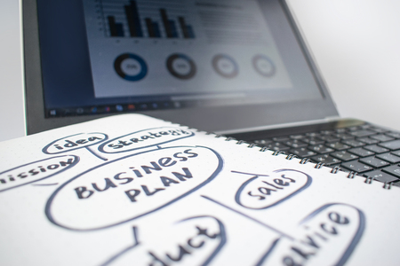Minimalistic workplace concept, with a laptop, pen and business work records on a white background. Image of business plan, startup. Close up image.の写真素材