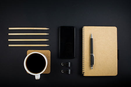 Minimalistic workplace concept, with a smartphone, pen and business work records on a dark background. Image of business plan, startup. Top view. Flat lay styleの写真素材