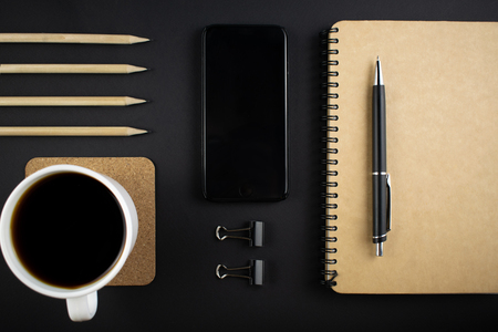 Minimalistic workplace concept, with a smartphone, pen and business work records on a dark background. Image of business plan, startup. Top view. Flat lay styleの写真素材