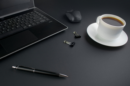 Minimalistic workplace concept, with a laptop, pen and business work records on a dark background. Image of business plan, startup. Close up image.の写真素材