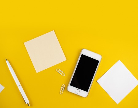 Minimalistic workplace concept, with a smartphone, pen and business work records on a dark background. Image digital, marketing, design agency. Top view. Flat lay styleの写真素材