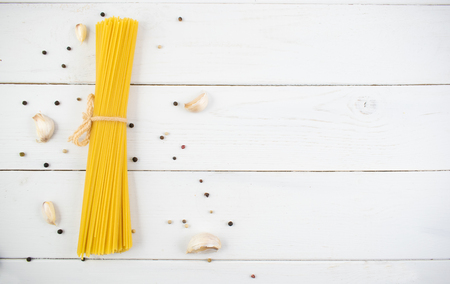Bunch of long dry spaghetti on a white wooden table. Italian cuisine concept, food ingredients. Flat lay. Top view.の写真素材