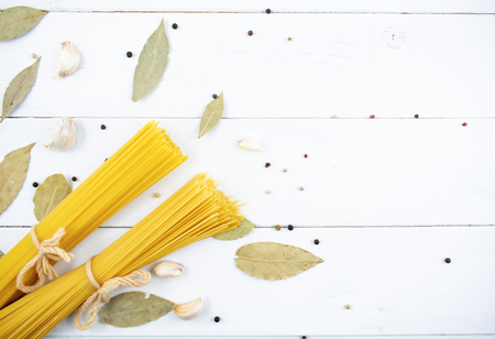 Bunch of long dry spaghetti on a white wooden table. Italian cuisine concept, food ingredients. Flat lay. Top view, copy space.の写真素材