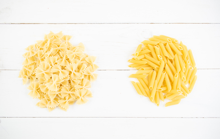 Various types of pasta on a white wooden table. Italian cuisine concept, food ingredients. Flat lay. Top view, copy space.の写真素材