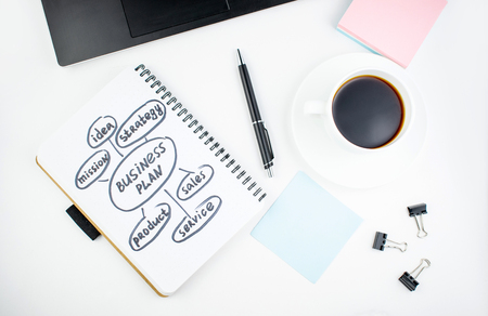 Minimalistic workplace concept, with a laptop, pen and business work records on a white background. Image of business plan, startup. Close up image.の写真素材