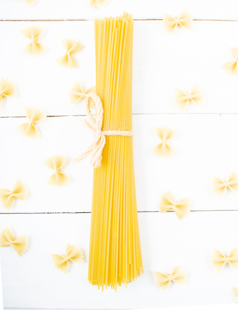 Bunch of long dry spaghetti on a white wooden table. Italian cuisine concept, food ingredients. Flat lay. Top view.の写真素材