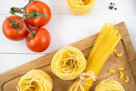 Various types of pasta on a white wooden table. Italian cuisine concept, food ingredients. Flat lay. Top view, copy space.の写真素材