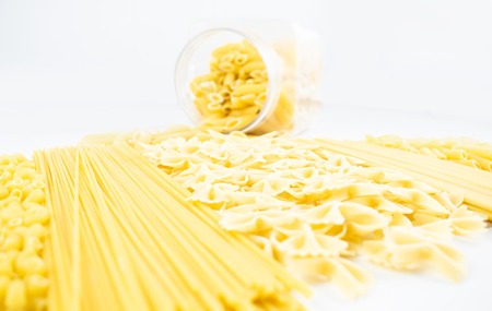 Various types of pasta on a white wooden table. Italian cuisine concept, food ingredients. Flat lay. Top view, copy space.の写真素材