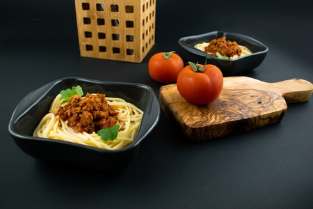 Spaghetti bolognese on a plate on wooden dark background. Italian cuisine concept, food ingredients. Close up view.の写真素材