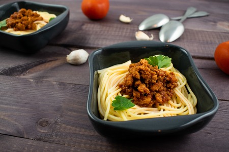 Spaghetti bolognese on a plate on wooden dark background. Italian cuisine concept, food ingredients. Close up view.の写真素材