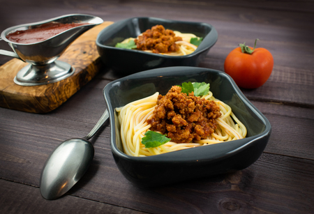 Spaghetti bolognese on a plate on wooden dark background. Italian cuisine concept, food ingredients. Close up view.の写真素材