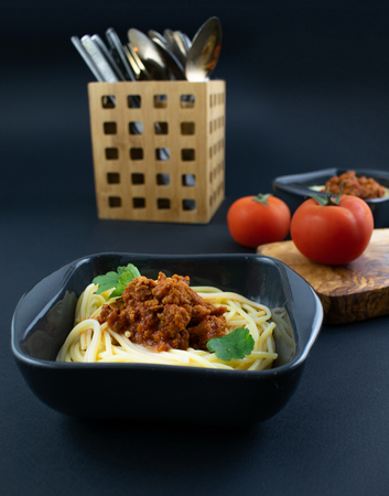 Spaghetti bolognese on a plate on wooden dark background. Italian cuisine concept, food ingredients. Close up view.の写真素材
