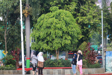 Kudus, December 2022. Photograph of visitors sitting relaxed enjoying the afternoon on the grass of the Kudus city square.の写真素材