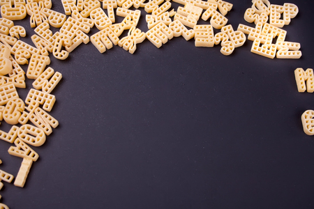 Raw macaroni alphabet frame on black backgroundの写真素材