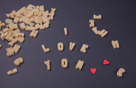 Text I love you written with macaroni in the form of letters on black wooden table backgroundの写真素材