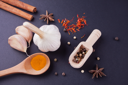 Various spices with wooden spoons on a black tableの写真素材