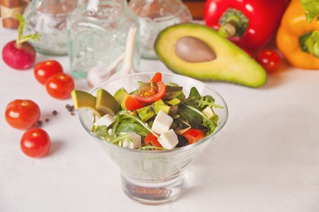 Fresh mixed vegetables salad in a bowl with vegetables on the backgroundの写真素材