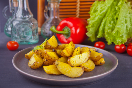 Homemade baked organic potato wedges with herbs on a gray plateの写真素材