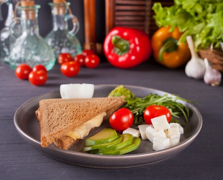 Sandwich with vegetables on a black plate with vegetables on the backgroundの写真素材