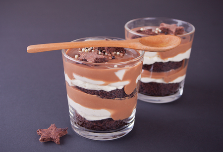 Chocolate dessert in glass jars on a table with wooden spoonの写真素材