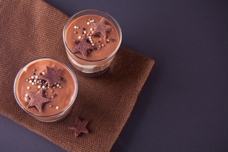 Chocolate dessert in glass jars on a table with wooden spoon. Top view.の写真素材