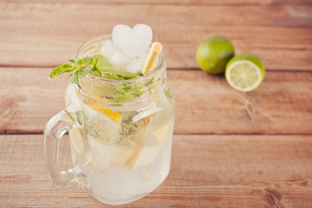Lemonade or mojito cocktail with lemon and mint, cold refreshing drink or beverage with ice heart shaped .の写真素材