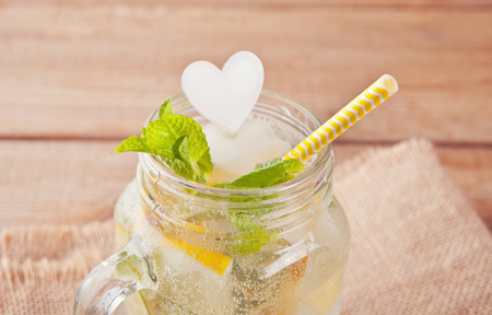 Lemonade or mojito cocktail with lemon and mint, cold refreshing drink or beverage with ice heart shaped .の写真素材