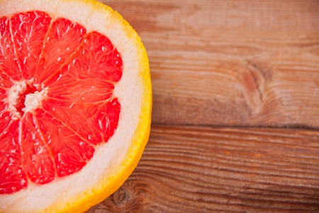 Slice of fresh red grapefruit on old wooden table. Top view.の写真素材