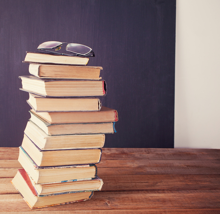 old books row and eye glasses on the chalkboard backgroundの写真素材