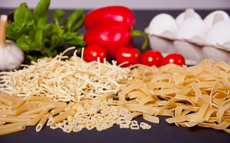 Vegetables and pasta on the black tableの写真素材