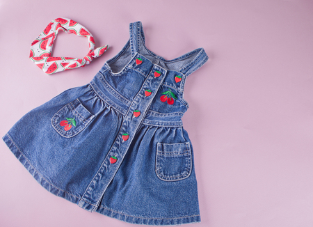 Baby denim dress with berries and accessorie headband on the pink background. Top view.の写真素材