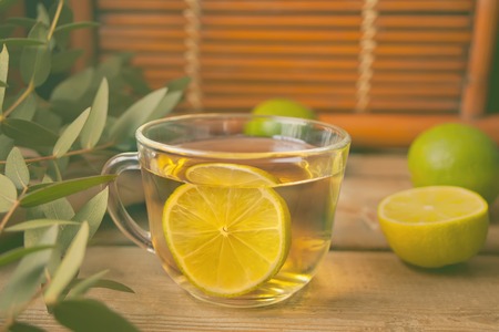 Cup of green tea with lime on the old wooden tableの写真素材