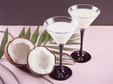 Pina Colada tropical cocktail with palm leaf and coconut on the backgroundの写真素材