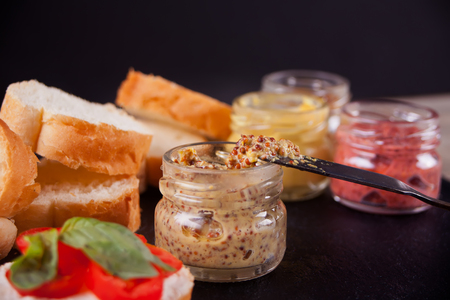 Set of mustard with buns, basil on black plate. For homemade bruschetta.の写真素材