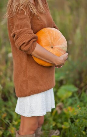 Woman with a ripe pumpkin in a garden. Autumn harvest. Autumn concept.の写真素材