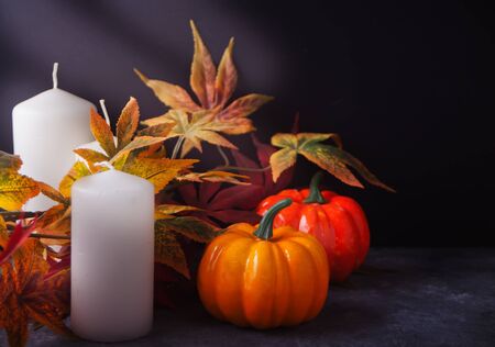 Cozy and warm composition with candles, autumn leaves, pumpkins on the dark background. Autumn concept. Copy space.の写真素材