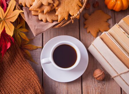 Composition with cup of coffee, autumn leaves, pumpkin, homemade cookies and books on the wooden table. Autumn concept. Top view.の写真素材