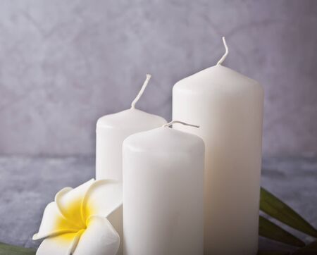 Three white candles, plumeria tropical flower on the gray background. Spa therapy conceptの写真素材