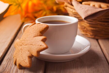 Cozy and warm composition with cup of coffee, autumn leaves, homemade cookies on the wooden table. Autumn concept.の写真素材
