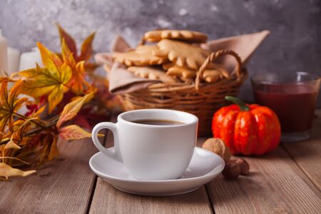 Cozy and warm composition with cup of coffee, autumn leaves, homemade cookies on the wooden table. Autumn concept.の写真素材