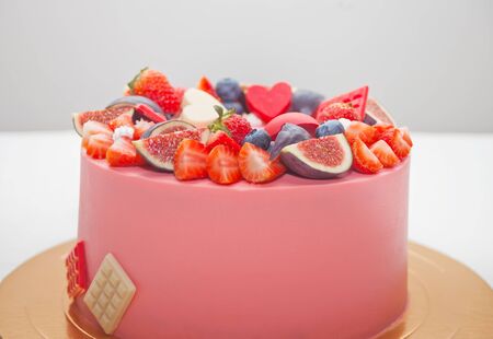 Close up pink cake decorated berries and fruits and chocolate.の写真素材