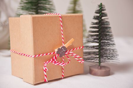 Christmas gift box on the light background with three small Christmas tree toys.