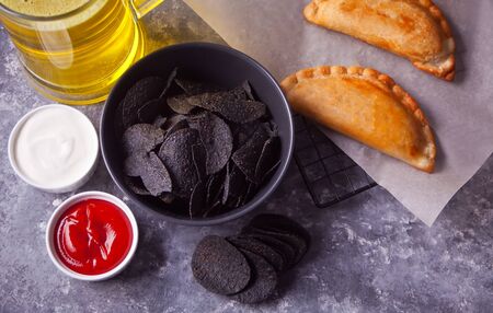 Mexican corn chips nachos and fried meat pies empanadas cheburek with dips. Black chips nachos for...